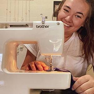 Ashley Buchholz smiles from behind her sewing machine.